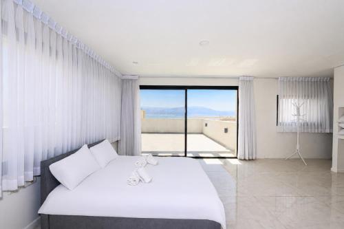 a white bedroom with a large bed and a balcony at זוהר על הים - ווילה ו-3 חדרי סטודיו מהממים עם בריכה בנווה זוהר in Neve Zohar
