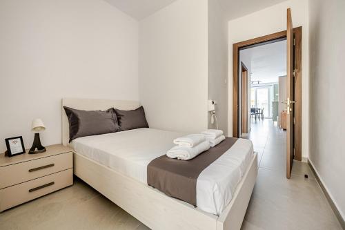 a white bedroom with a bed with towels on it at GZIRA F52 Bedroom in pethouse in Il-Gżira