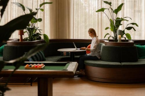 a woman sitting on a couch with a laptop at Habyt Vienna in Vienna