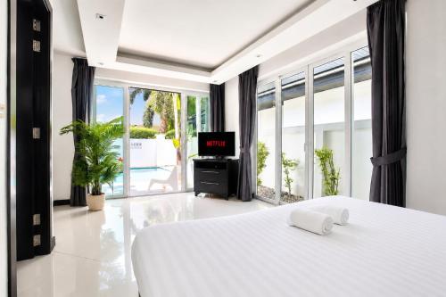 a bedroom with a bed and a tv in it at Pool Villa Pattaya Jomtien Beach - Palm Oasis C4 in Jomtien Beach