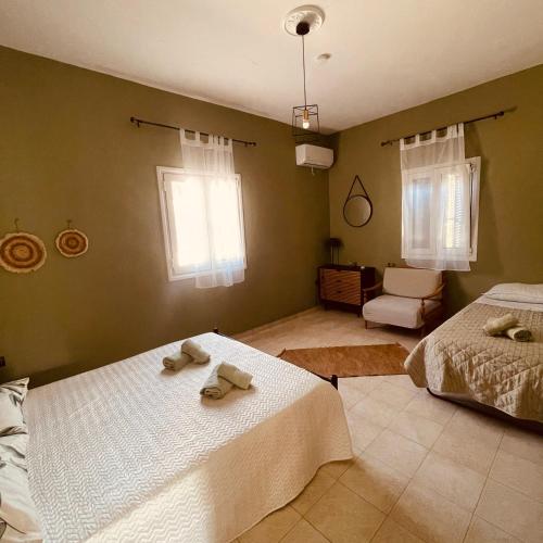 a bedroom with two beds and a chair and window at Casa Bellina ,Potamos Private Garden & Free Parking in Evropoúloi