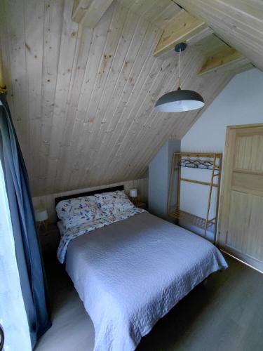 a bed in a room with a wooden ceiling at Borówkowa Dolina in Lądek-Zdrój