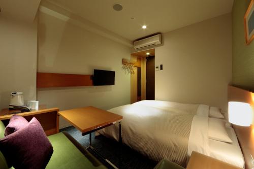a hotel room with a bed and a table and chairs at Candeo Hotels Fukuyama in Fukuyama