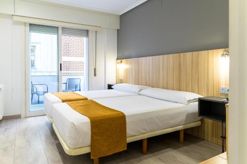 a bedroom with a large bed and a balcony at Alda Altiana in Ourense
