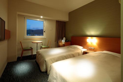 a hotel room with two beds and a window at Candeo Hotels Fukuyama in Fukuyama