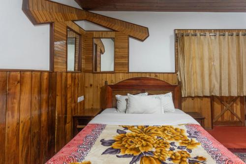 a bedroom with a bed with a flower blanket on it at Lilly's Valley Resort in Kodaikānāl