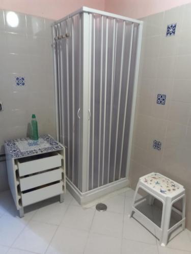 a bathroom with a shower and a sink and a stool at Green House in Briatico