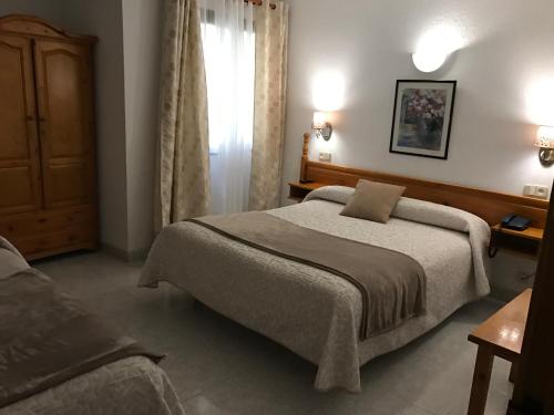 Un dormitorio con una cama grande y una ventana. en Hostal Alcázar, en Toledo