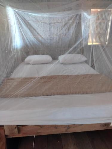 a bed with two pillows and a mosquito net at Kafdarun Homestay in Dokkor
