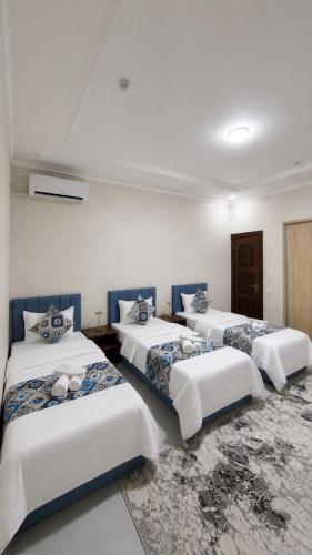 a room with three beds in a room at Abuzar in Bukhara