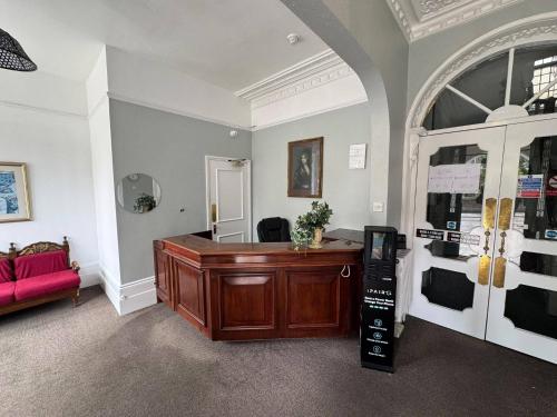 a room with a desk and a red couch at The Kirkdale Hotel in Croydon
