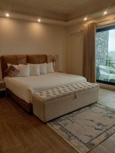 a bedroom with a large bed with a large window at The Bliss avenue in Murree