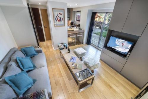 a living room with a couch and a flat screen tv at Résidence Les Sapins - Courchevel 1850 in Courchevel