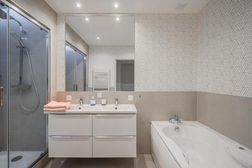 a bathroom with a tub and a sink and a bath tub at Au coeur de Valence - Parking gratuit - Entièrement climatisé in Valence
