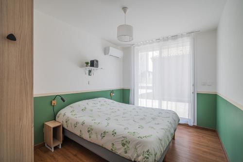 a bedroom with a bed with green and white sheets at Au coeur de Valence - Parking gratuit - Entièrement climatisé in Valence