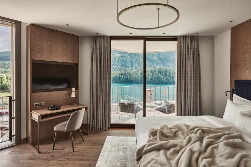 a bedroom with a bed and a desk with a view at Hotel GRACE LA MARGNA ST MORITZ in St. Moritz