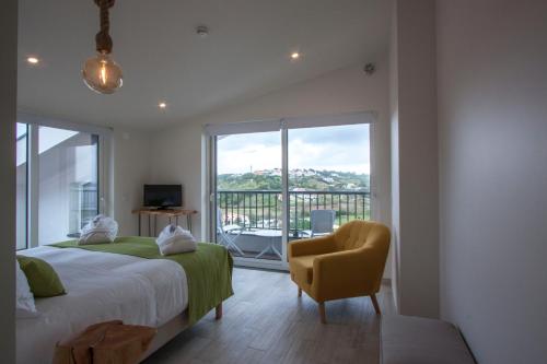 a bedroom with a bed and a chair and a window at Hillside House Residence in Foz do Arelho