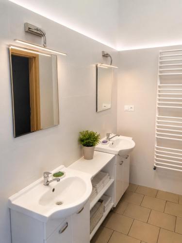 a white bathroom with two sinks and a mirror at Kwatery pracownicze in Łódź