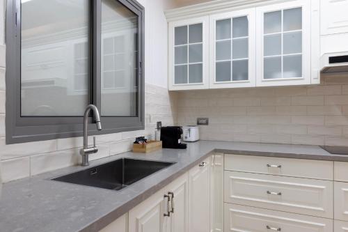 a kitchen with a sink and white cabinets at שאנל דירת גן עם בריכה in Eilat