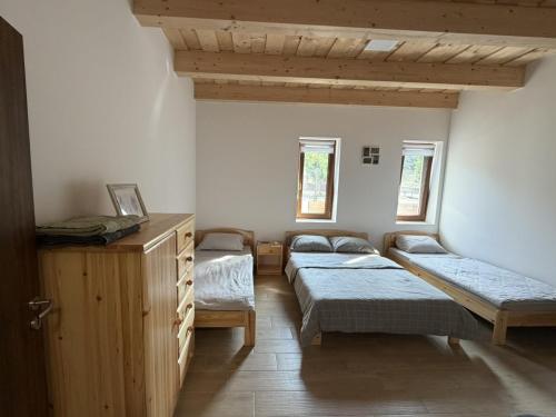 a room with three beds and a dresser and two windows at Csitári-patak Vendégház in Csitár