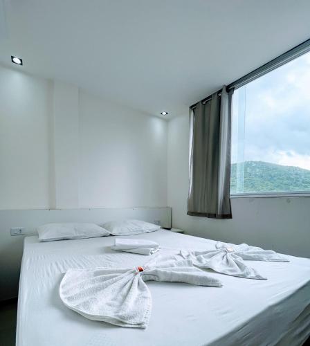 a bedroom with a bed with white sheets and a window at Princesa do Sertão Pousada in Palmeira dos Índios