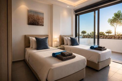 two beds in a room with a large window at Blue Infinity Villa 33 in Neo Chorio