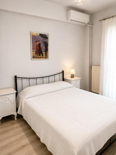 a bedroom with a white bed and a picture on the wall at Vathy Central Residence in Samos
