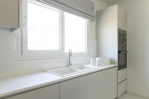 a white kitchen with a sink and a window at Azoria Villa in Haraki