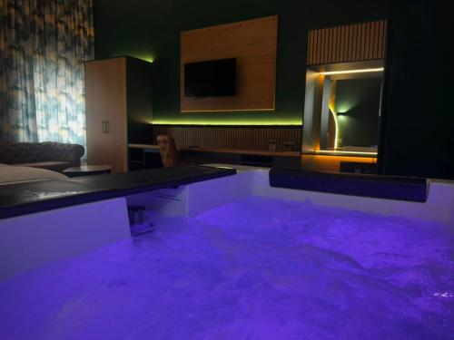 a room with a purple floor with a table and a tv at Hotel Zouk Suite Spa in Alba Iulia