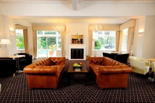 a living room with two leather couches and a fireplace at Burley Court Hotel in Bournemouth