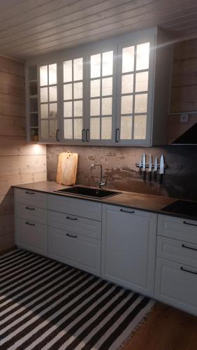 a kitchen with white cabinets and a sink and windows at Kloogaranna Seaside Cottage in Kloogaranna