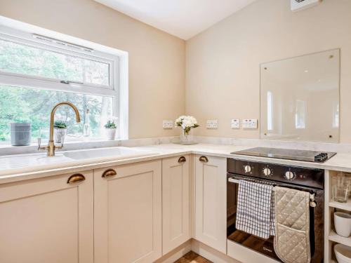 a kitchen with white cabinets and a sink and a window at Upper Hillside Cottage in Blairgowrie