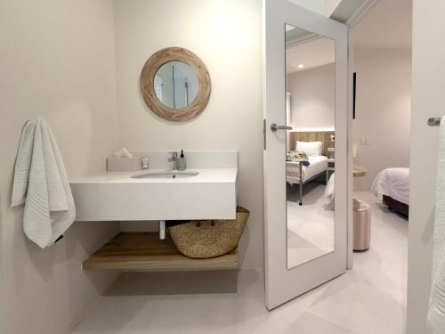 a white bathroom with a sink and a mirror at Plett Beachfront Guest House in Plettenberg Bay