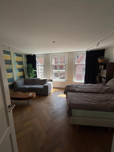 a bedroom with a bed and a living room with a couch at Zwols stadshuis in Zwolle