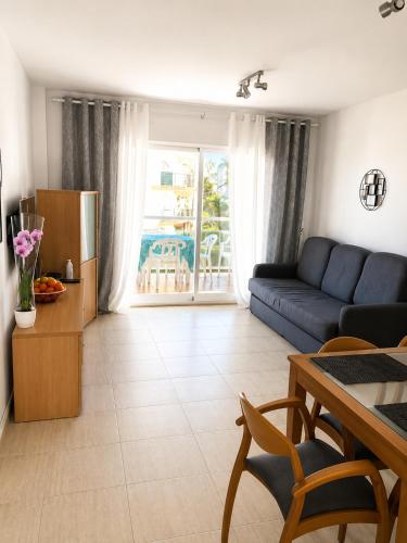 a living room with a blue couch and a table at Dénia Palm Garden Apartment Pool & Parking in Denia
