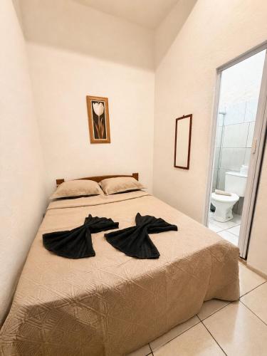 a bedroom with a bed with black robes on it at Pousada Gire in Itacaré