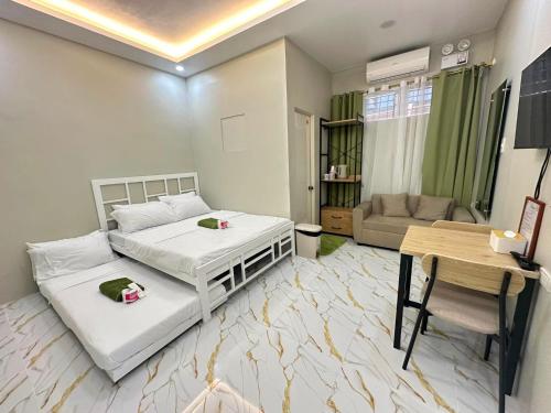 a bedroom with two beds and a table and a couch at Green Meadows Residence Naga in Milaor