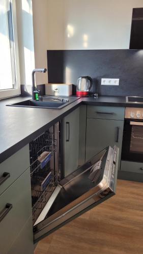 an open dishwasher in a kitchen with a sink at Sonnenstüble in Eriskirch