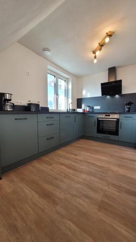 a large kitchen with white cabinets and a wooden floor at Sonnenstüble in Eriskirch