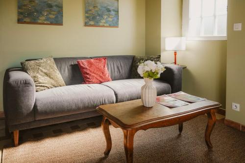 a living room with a couch and a table with a vase of flowers at Gîte Les Fresnes in Sainte-Honorine-des-Pertes
