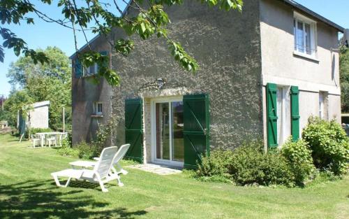a pair of white chairs in front of a house at Gîte Les Fresnes in Sainte-Honorine-des-Pertes