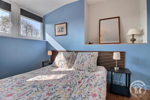 a blue bedroom with a bed and a mirror at Kermaria la maison d'hôtes in Plougrescant
