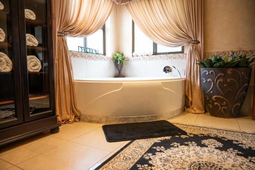 a bath tub in a bathroom with a window at Tuscan Rose in Bloemfontein