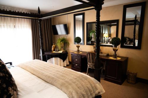 a bedroom with a bed and a desk and mirror at Tuscan Rose in Bloemfontein