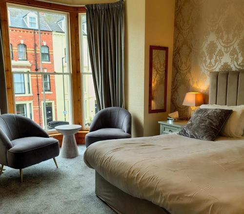a bedroom with a bed and two chairs and a window at Pinewood House in Whitby