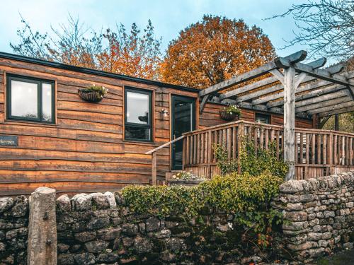 a log cabin with a porch and a stone wall at The Game Keeper - Uk50611 in Sabden
