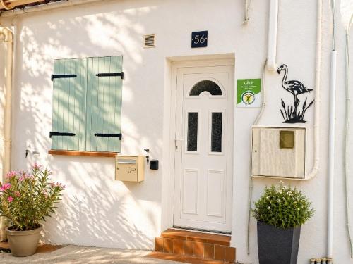 a white building with a door and a bird on it at Maison le Flamant in Port-Saint-Louis-du-Rhône
