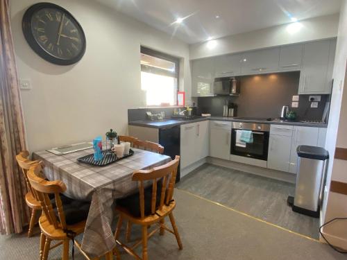 a kitchen with a table and a clock on the wall at Puffin - Bach in Lerags