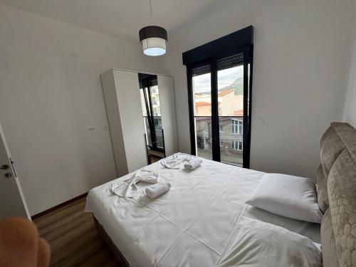a bedroom with a bed with white sheets and a window at Florida Apartments with PARKING in Dobra Voda
