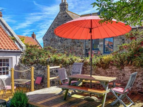 a table and chairs with an umbrella on a deck at Lee Cottage - E4343A in Holy Island